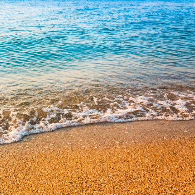 Foto suaves ondas do oceano lavam sobre fundo de areia dourada