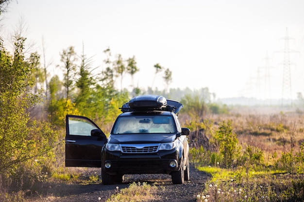 Subaru Forester com caixa de telhado em estrada de terra na floresta