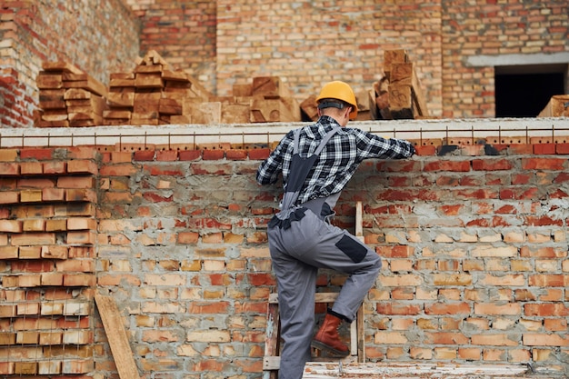 Sube al trabajador de la construcción en uniforme y equipo de seguridad tiene trabajo en la construcción