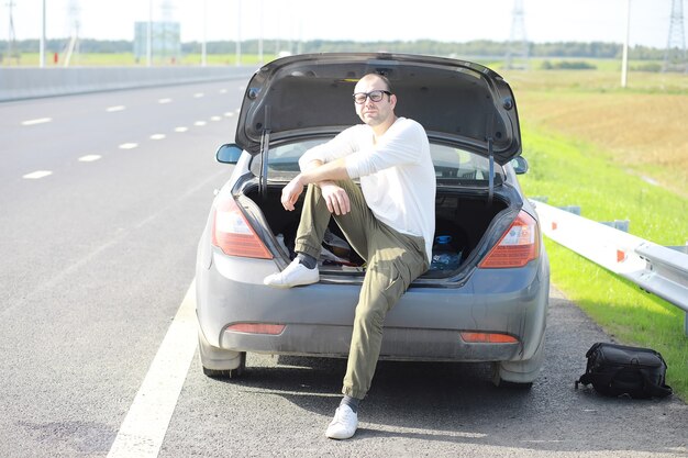 Substituindo a roda de um carro na estrada. Um homem trabalhando nos pneus do lado de fora.