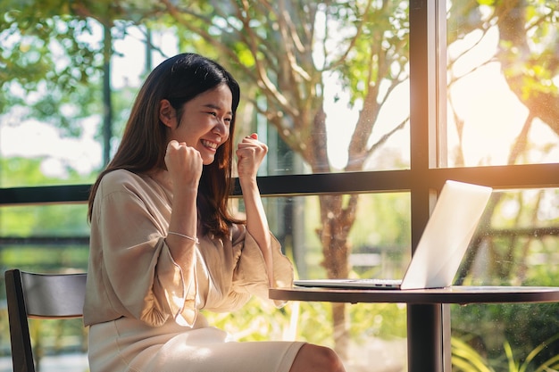 Foto sucesso de felicidade empresária asiática feliz enquanto usa laptop para resultados de negócios