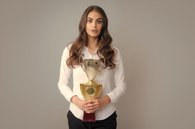 Sucesso do vencedor do conceito de mulher de negócios vitória da mulher de negócios fêmea com troféu isolado em fundo cinza empregado de sucesso detém a taça do vencedor cerimônia de premiação para o vencedor