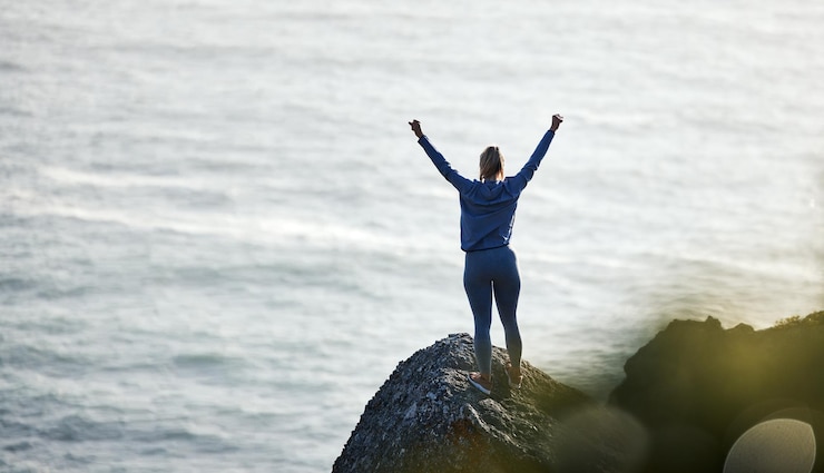 Foto sucesso oceano e rocha com mulher caminhando para liberdade de viagem ou férias de treinamento treino de saúde e silhueta com atleta de menina em aventura na paisagem para motivação vencedora ou exercício na natureza
