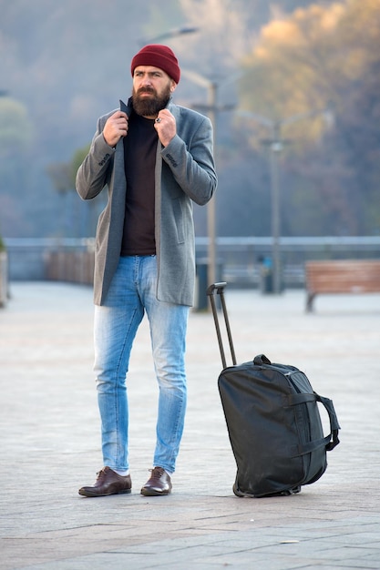 Suche nach Unterkunft Mann bärtiger Hipster reist mit großer Gepäcktasche wartet auf Taxi bringt ihn zum Hotel Reisetipps Reisender mit Koffer kommt am Reiseziel an Hipster bereit Reise zu genießen