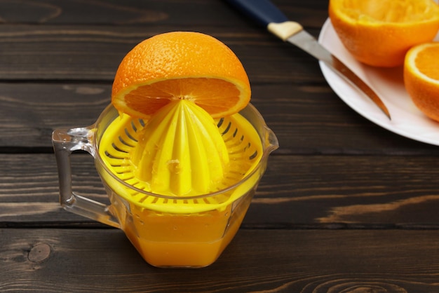 Suco artesanal, espremedor de frutas cítricas esprema suco fresco de metades de laranjas para nutrição saudável, na superfície marrom de madeira