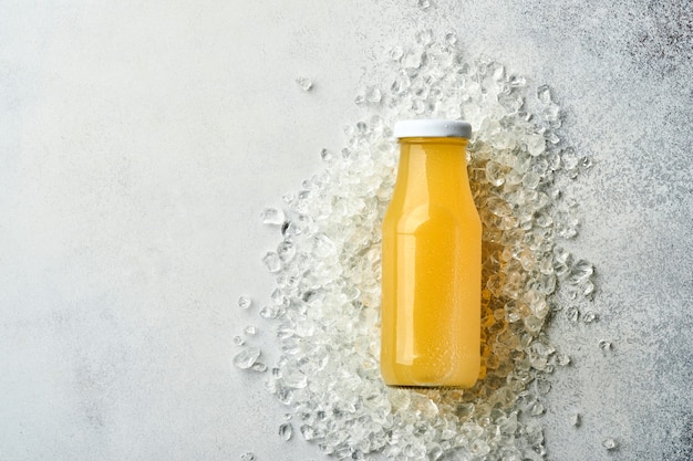 Suco de abacaxi fresco em frasco de vidro com gelo e variedade em fatias maduras de toranja de frutas tropicais de cor, laranja, limão, limão, composição plana leiga, sobre fundo de pedra cinza claro.