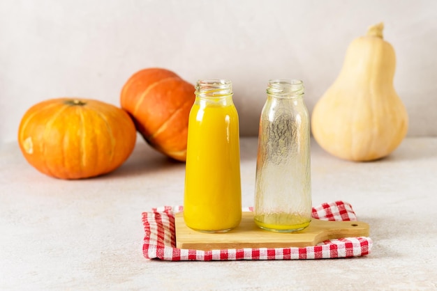 Suco de abóbora espremido na garrafa de vidro com suco amarelo no guardanapo de bandeja de madeira