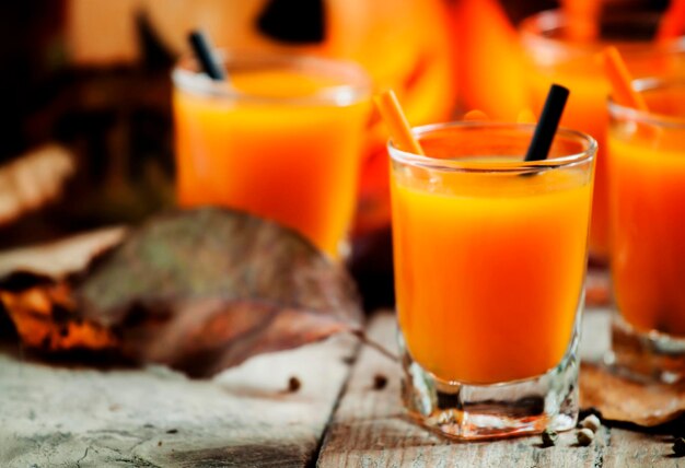 Suco de abóbora fresco em um fundo escuro de Halloween com foco seletivo de velas queimadas