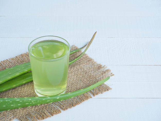 Suco de aloe vera e aloe vera fresca em saco de cânhamo em madeira