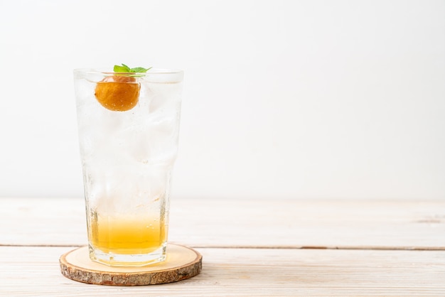 Suco de ameixa gelado com refrigerante e hortelã-pimenta na mesa de madeira. bebida refrescante