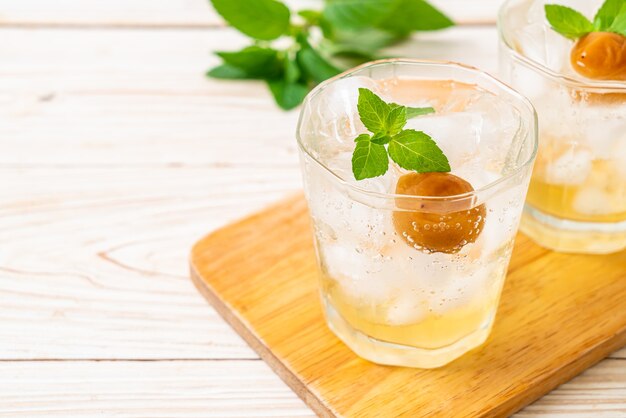 Suco de ameixa gelado com refrigerante e hortelã-pimenta na mesa de madeira - bebida refrescante