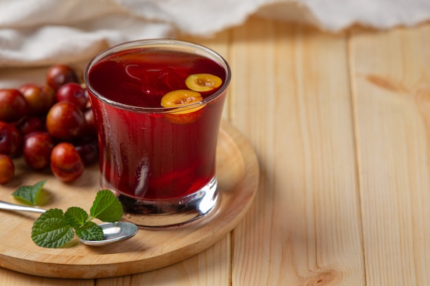 Suco de ameixas frescas na superfície de madeira.