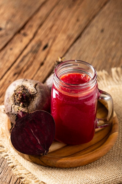 Foto suco de beterraba vermelha em copo de vidro sobre a mesa de madeira