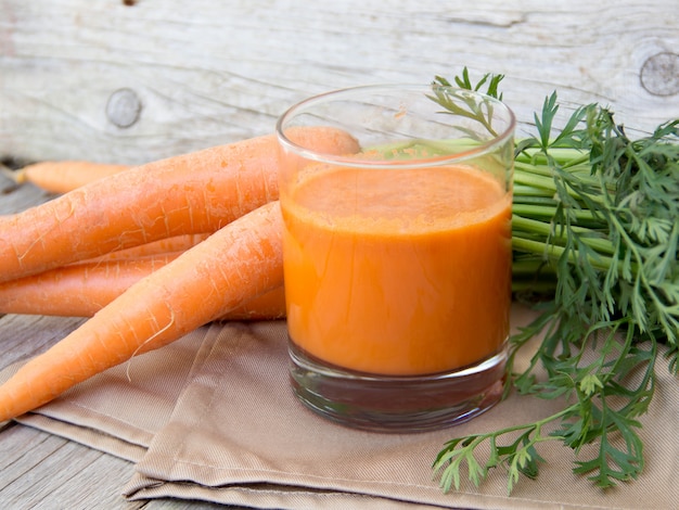 Suco de cenoura fresca em uma mesa de madeira fechar