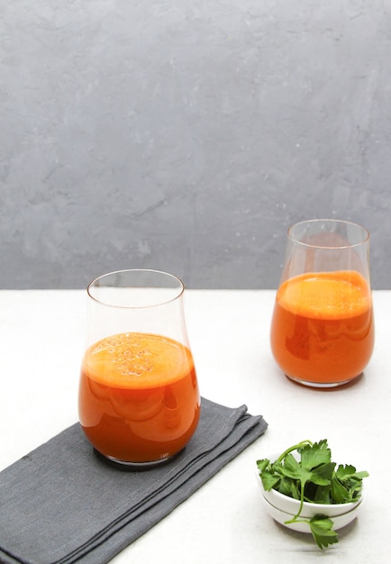 Suco de cenoura fresco em copos em uma superfície branca
