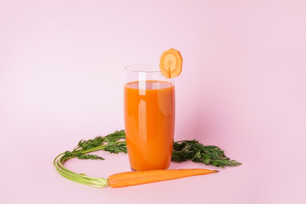 Suco de cenoura fresco em um copo de vidro e cenouras frescas
