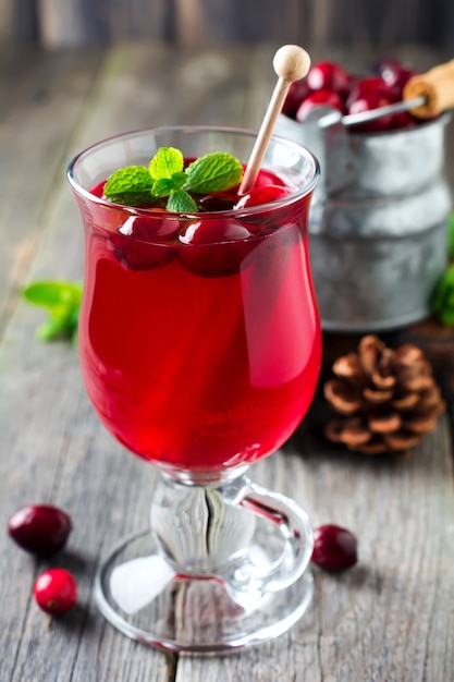 Suco de cranberry fresco com canela e anis em potes de vidro na superfície de madeira velha. foco seletivo.