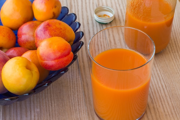 Suco de damasco e damascos em um vaso azul sobre branco