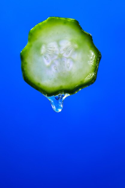 Suco de gel pinga de fatias de pepino com gel sobre fundo azul planta medicinal natural para cosméticos orgânicos medicina alternativa saúde e beleza spa conceito gota de pepino