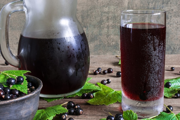 Suco de groselha preta fria em um copo e jarra