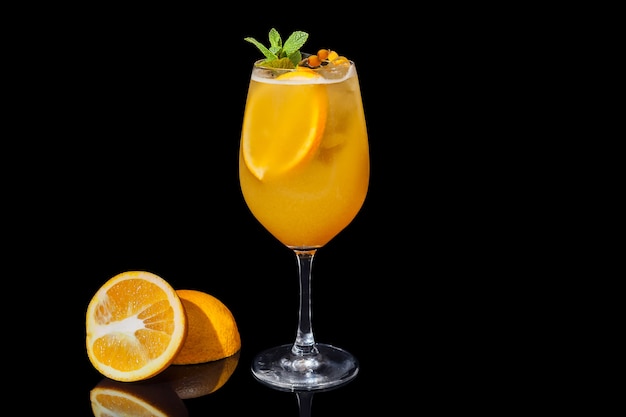 Suco de laranja com álcool em um fundo preto decorado com uma fatia de laranja e hortelã