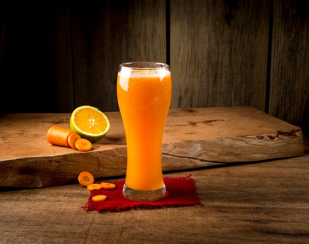 Suco de laranja com cenoura com rodelas de laranja e cenoura em fundo de madeira