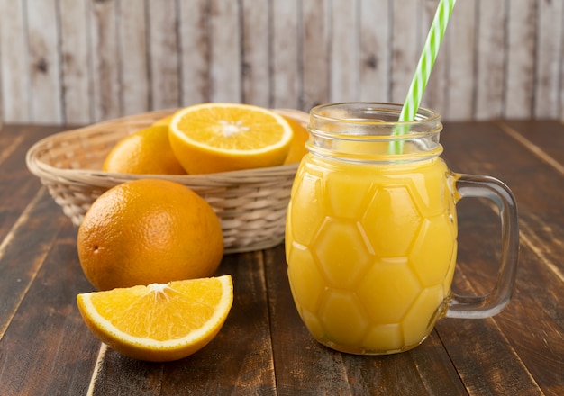 Suco de laranja com fatias de laranja sobre uma mesa de madeira.