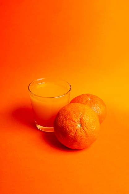 Suco de laranja com laranjas em fundo laranja