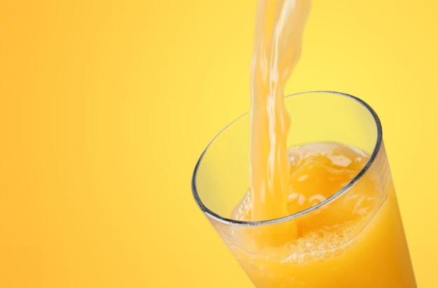 Suco de laranja derramando em um copo no fundo