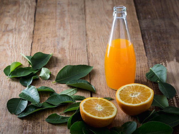 Foto suco de laranja e laranja com folhas no fundo de madeira