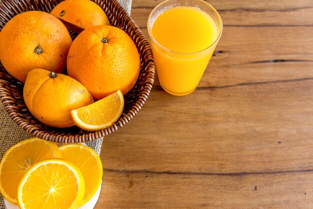 Suco de laranja e laranjas em fundo de madeira. Vista do topo.