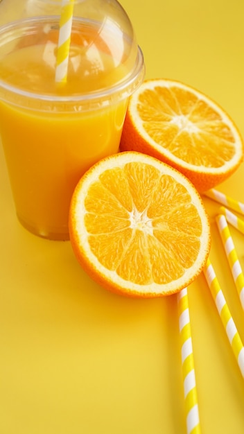 Suco de laranja em copo fechado de fast food com tubo em fundo amarelo. Canudos de papel laranja e amarelo fatiados para uma bebida. Foto vertical