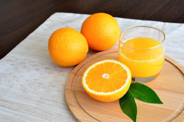 suco de laranja em copo na tábua isolada com laranjas na mesa da cozinha