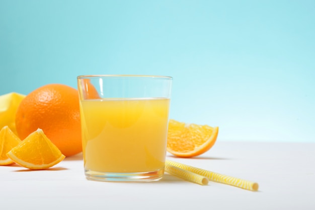 Suco de laranja em um copo de laranjas e rodelas de laranja na mesa