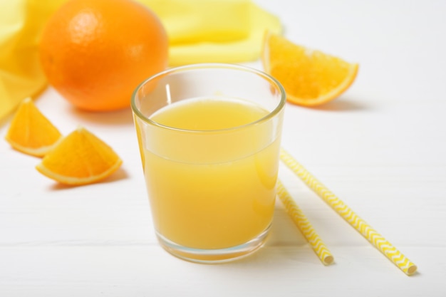 Suco de laranja em um copo de laranjas e rodelas de laranja na mesa