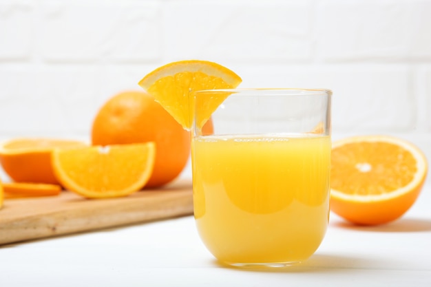 Suco de laranja em um copo de laranjas e rodelas de laranja na mesa