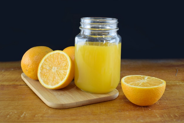 Suco de laranja em um copo de vidro com fatias de laranja em uma mesa de madeira