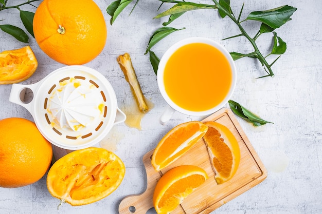 Suco de laranja espremido e frutas frescas das laranjas na tabela de madeira branca.