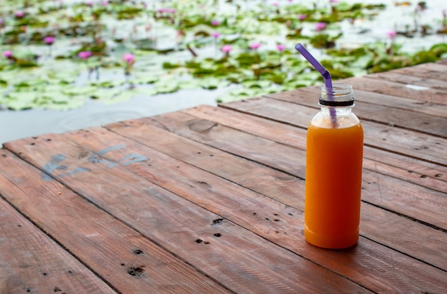 Suco de laranja fresco e fresco na garrafa de plástico na mesa de madeira