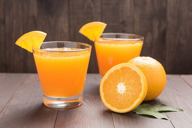 Suco de laranja fresco e laranjas na mesa de madeira