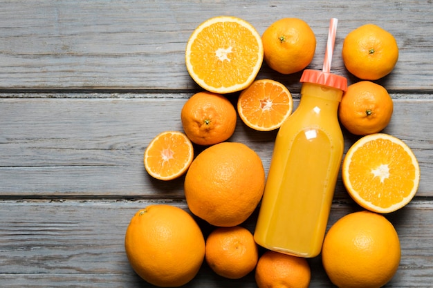 Suco de laranja fresco em uma garrafa com laranjas em um fundo de madeira rústico