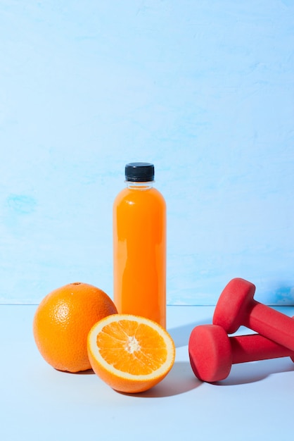 Suco de laranja natural fresco com halteres na mesa. Bebida saudável.