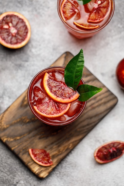 Suco de laranja no sangue com gelo e fatia de laranja. Cocktail de verão fresco com laranjas vermelhas em um copo.