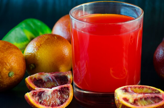 Suco de laranja siciliana e frutas frescas em um fundo preto