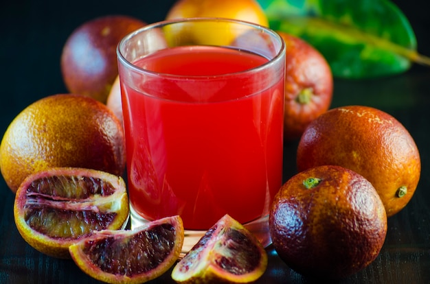 Suco de laranja siciliana e frutas frescas em um fundo preto