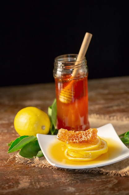 Suco de limão com mel na tabela de madeira, limões e folhas prudentes.