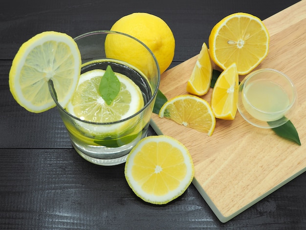Suco de limão fresco na tigela pequena e fatia de limão no fundo escuro de madeira