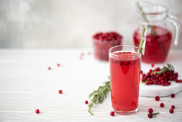 Suco de lingonberry com alecrim e mel em um prato de vidro em uma mesa branca