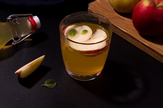 Suco de maçã caseiro em um copo ao lado de maçãs frescas.