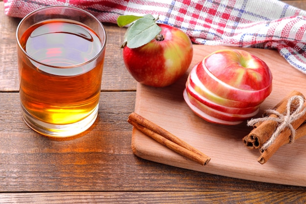 Foto suco de maçã com maçãs e canela em um fundo de madeira